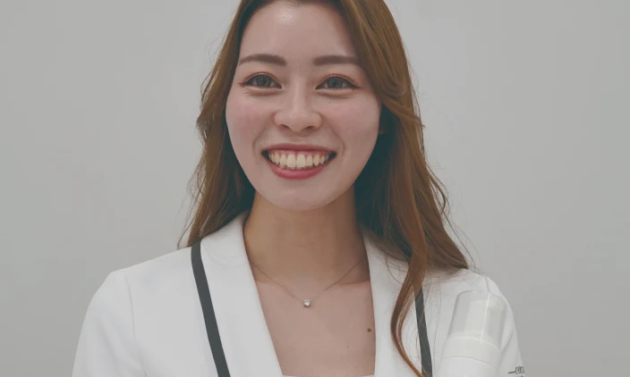 笑顔でこちらを向く白いジャケットを着た女性社員