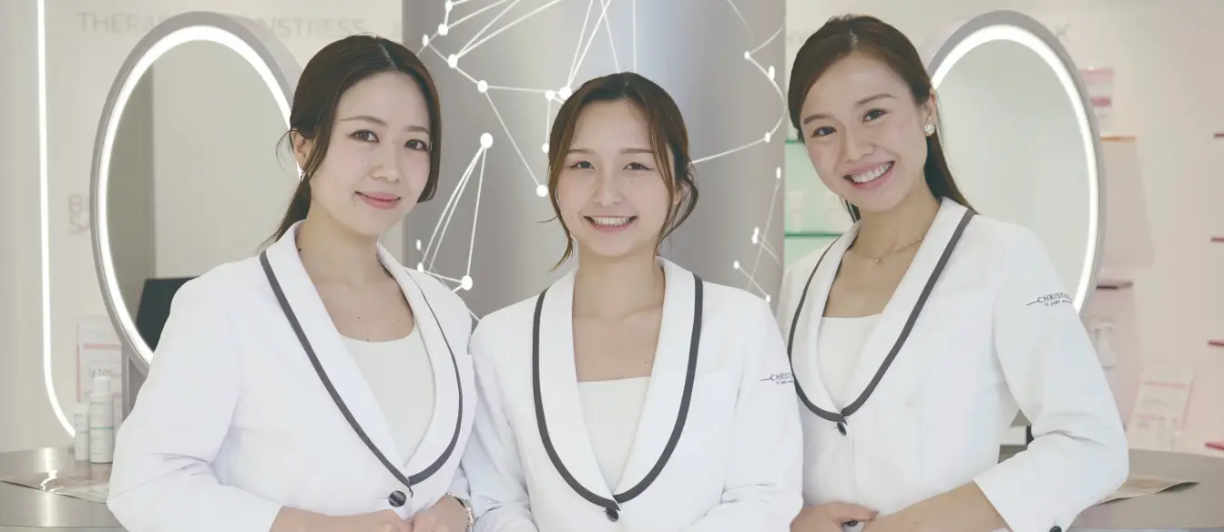 エステサロンの店内で笑顔で並ぶ白いユニフォーム姿の女性スタッフ3人